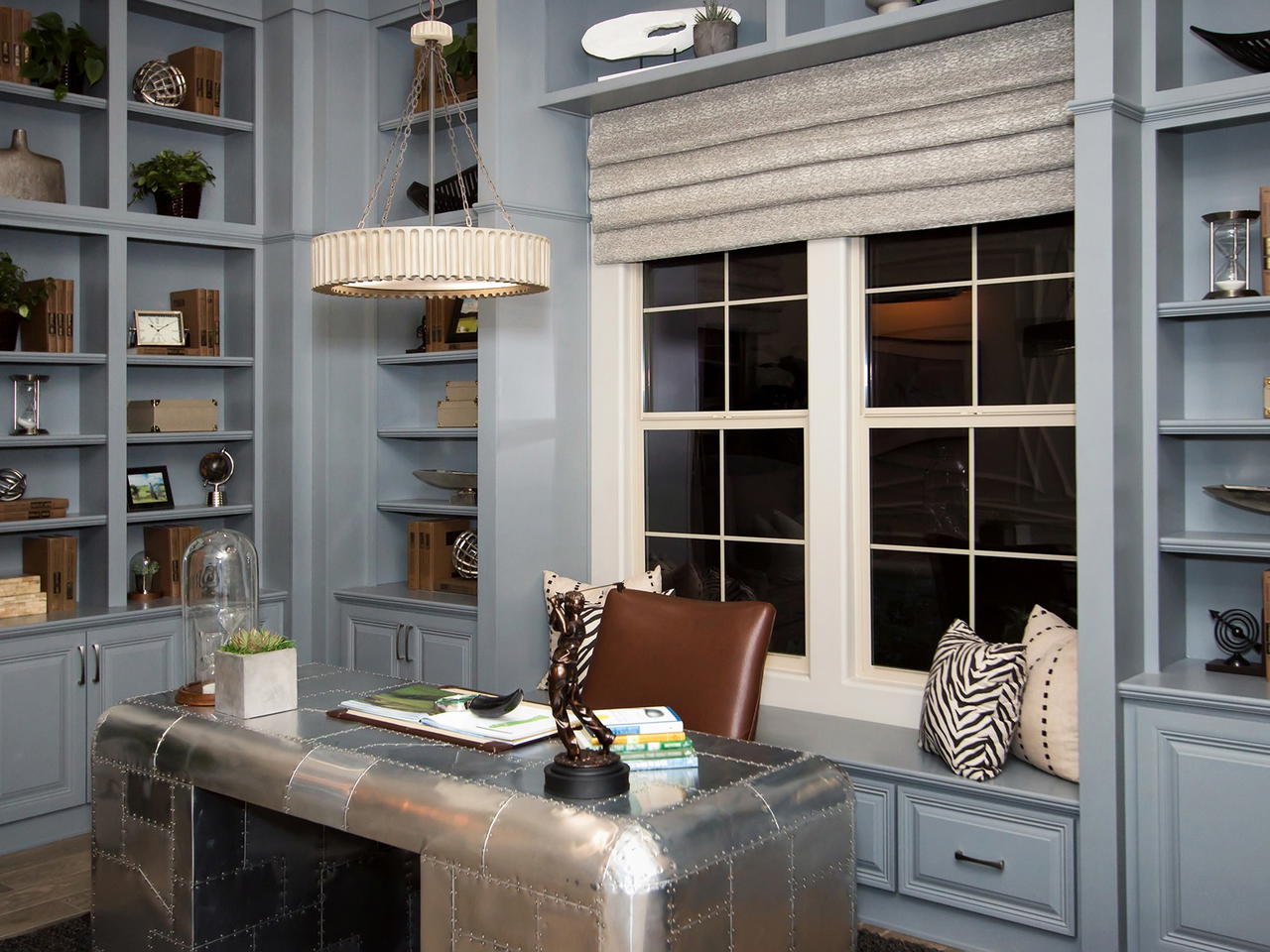 A modern home office with a metal desk, blue walls, and built-in shelves.
